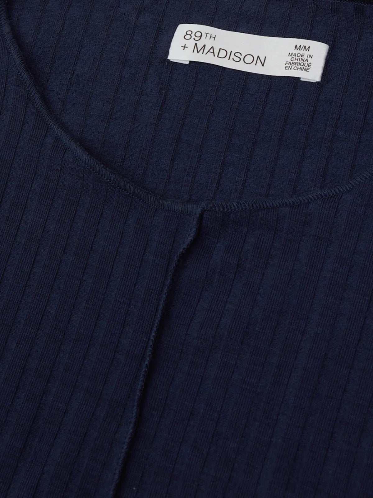 Navy ribbed sweater with a brand label on a matching background