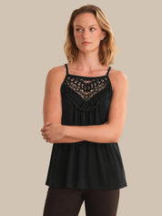 Woman wearing a black sleeveless top with lace details on a beige background
