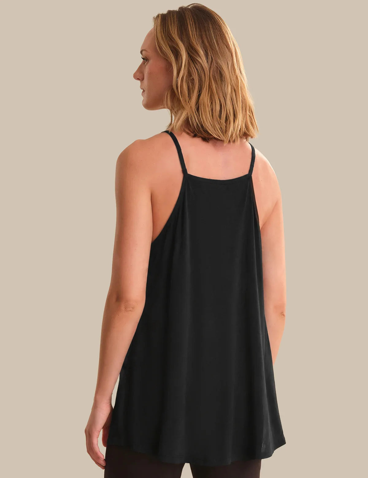 Woman wearing a black tank top against a neutral background