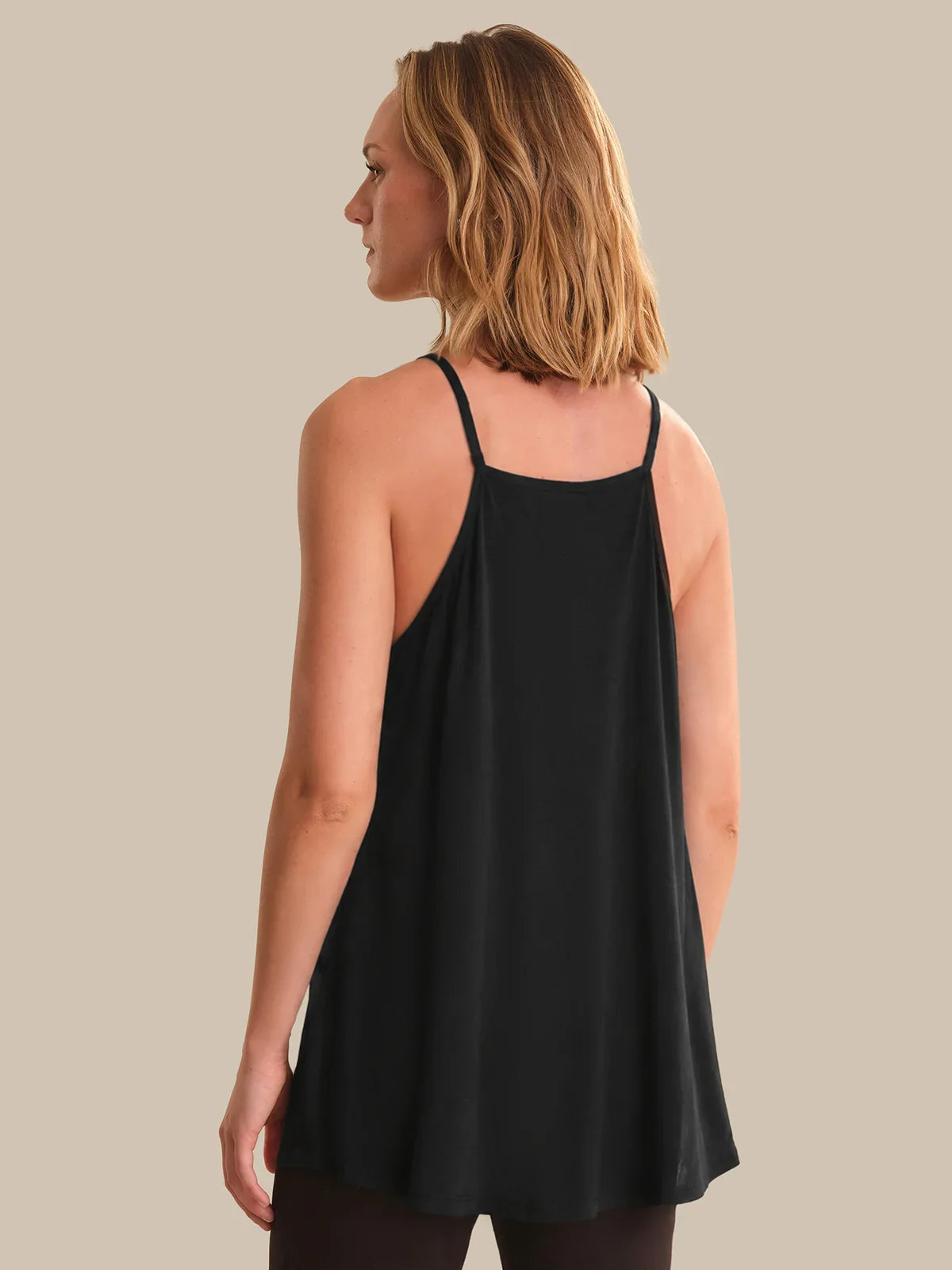 Woman wearing a black tank top against a neutral background