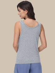 A woman shown from the back wearing a light gray heather sleeveless tank top and blue pants, set against a solid beige studio background.