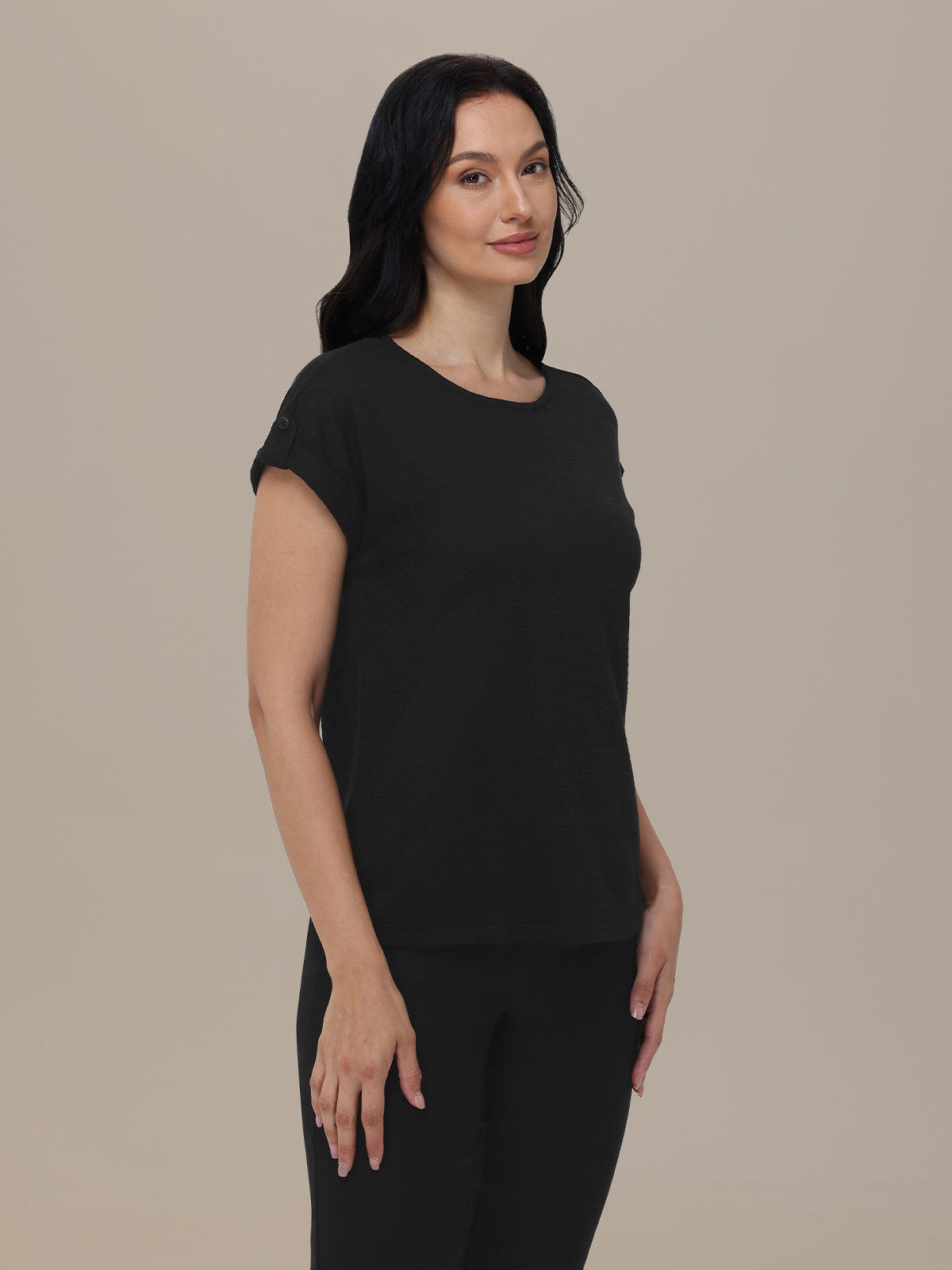 Woman wearing a black t-shirt and pants against a beige background