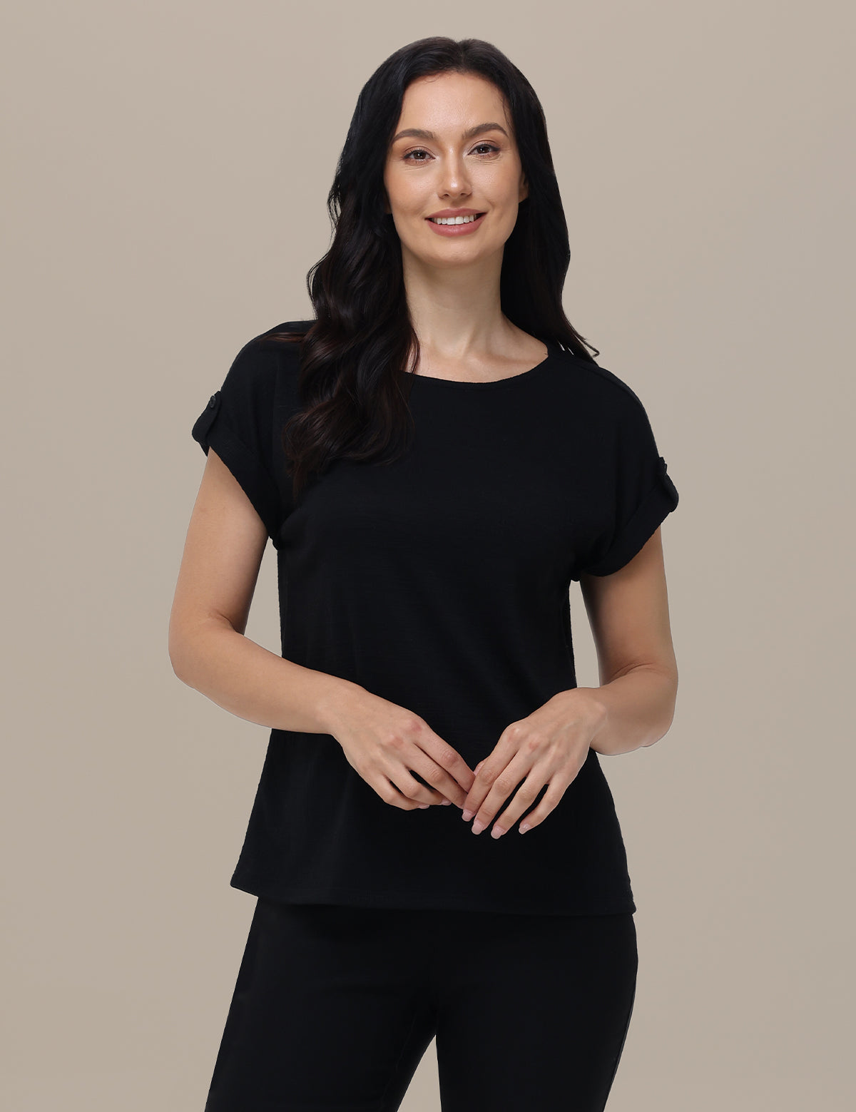 Woman wearing a black top with ruffled sleeves against a beige background