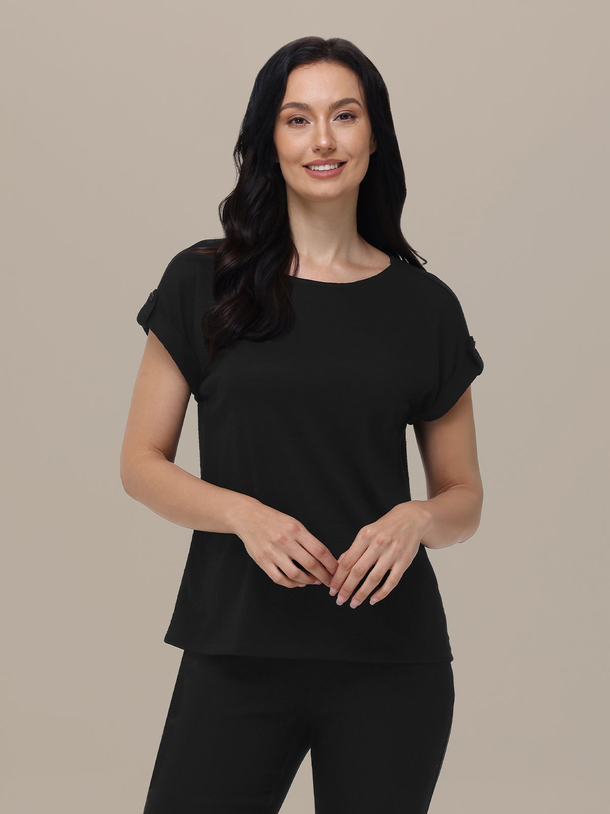 Woman wearing a black top with ruffled sleeves against a beige background