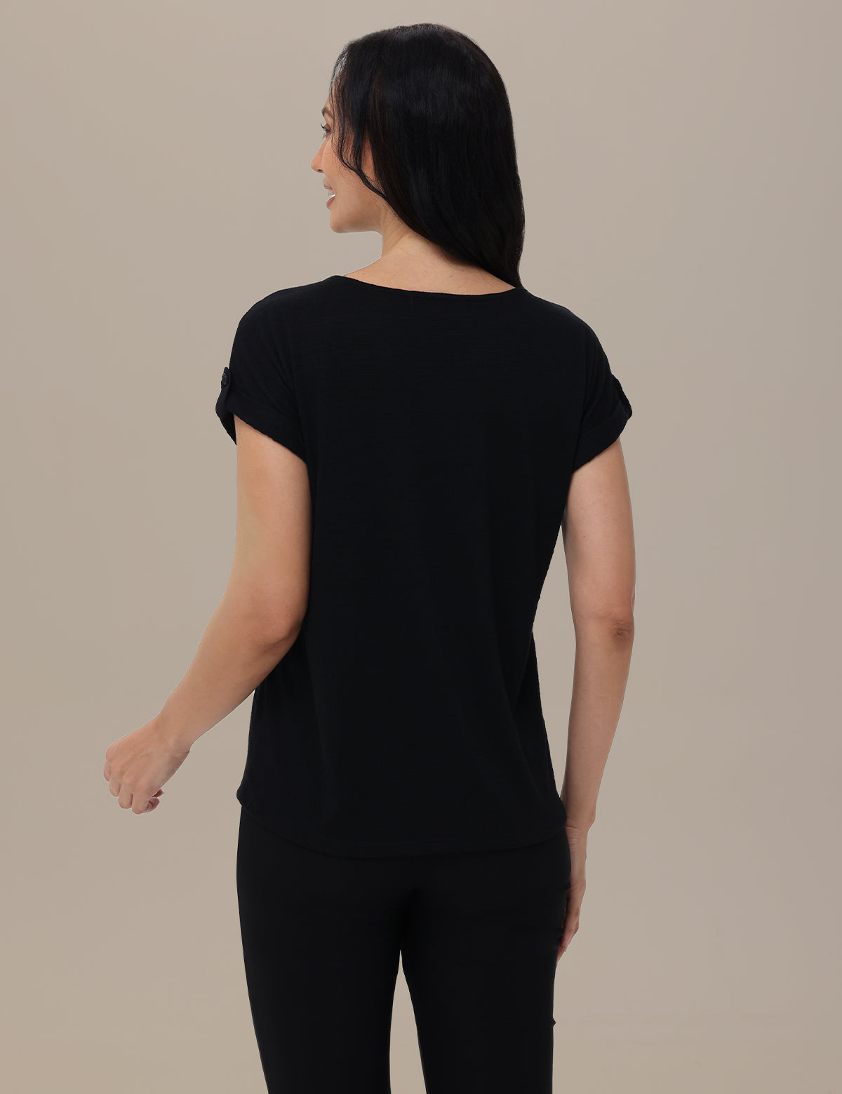Woman wearing a black t-shirt and pants on a beige background