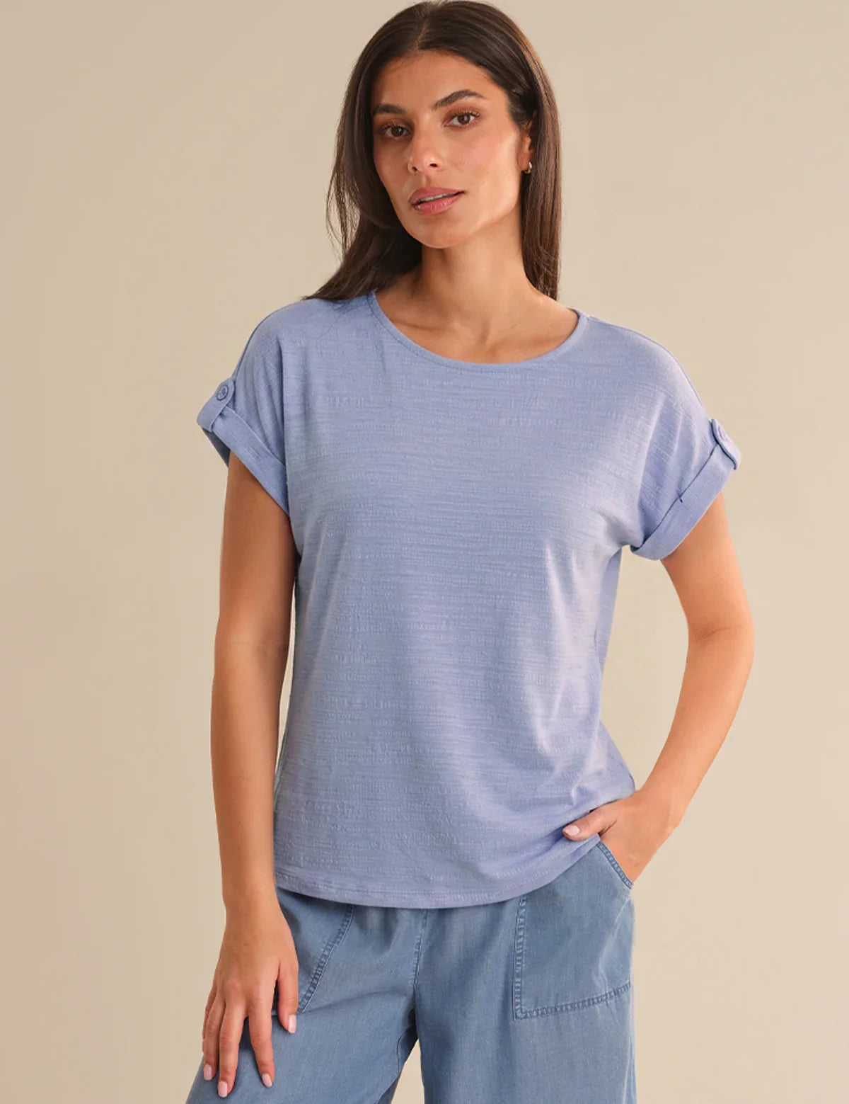 Woman wearing a light blue ruffled sleeve top against a beige background
