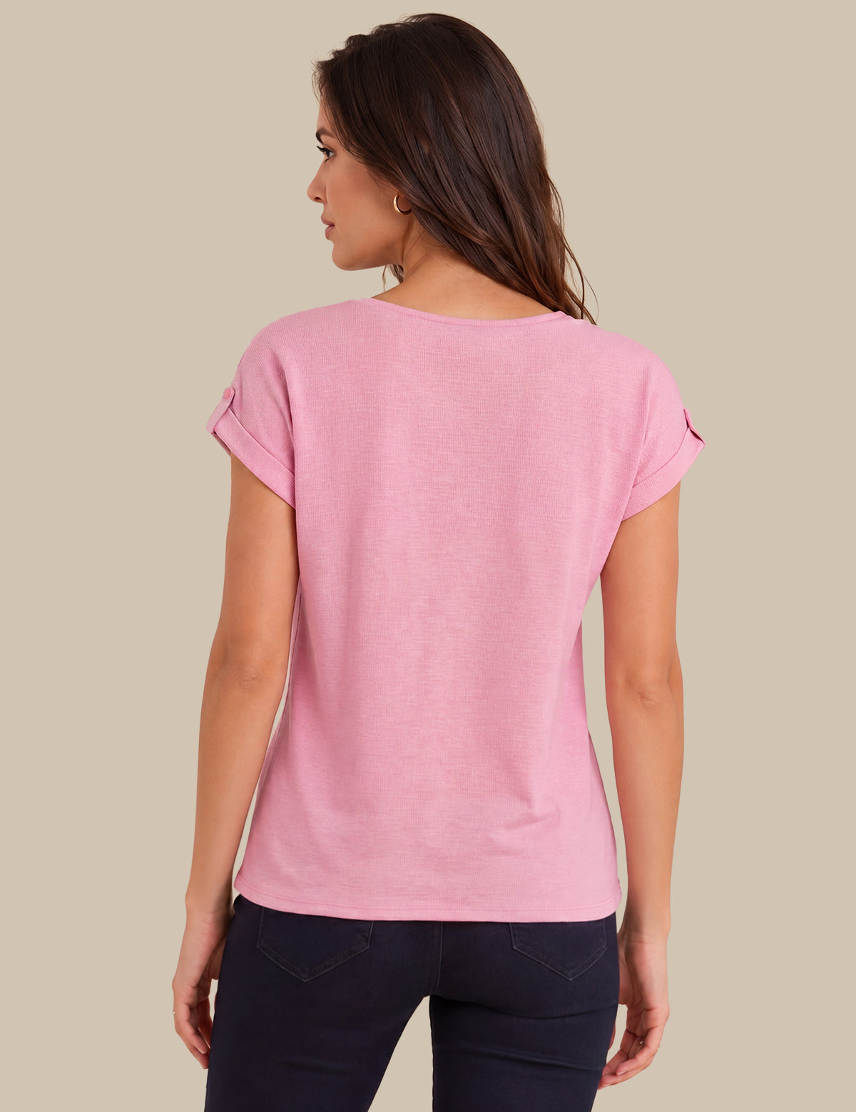 A woman shown from the back wearing a light pink short-sleeve t-shirt and dark navy pants, set against a solid beige background.