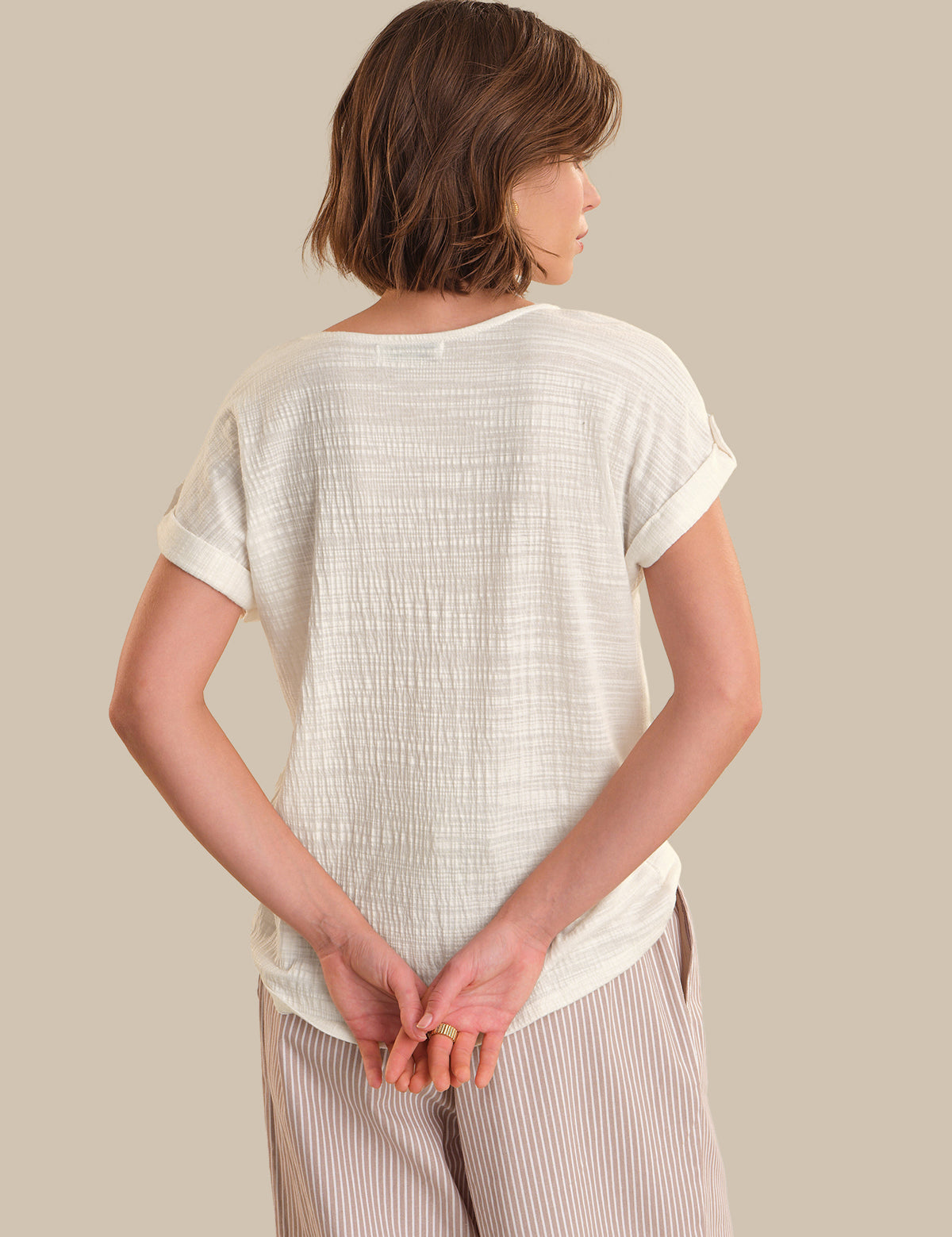 Person wearing a light-colored textured shirt and pants against a neutral background