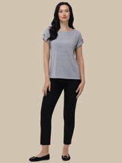 Woman wearing a gray striped shirt and black pants on a beige background