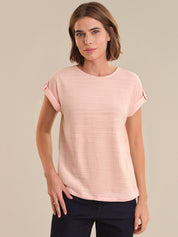 Woman wearing a pink textured top against a beige background