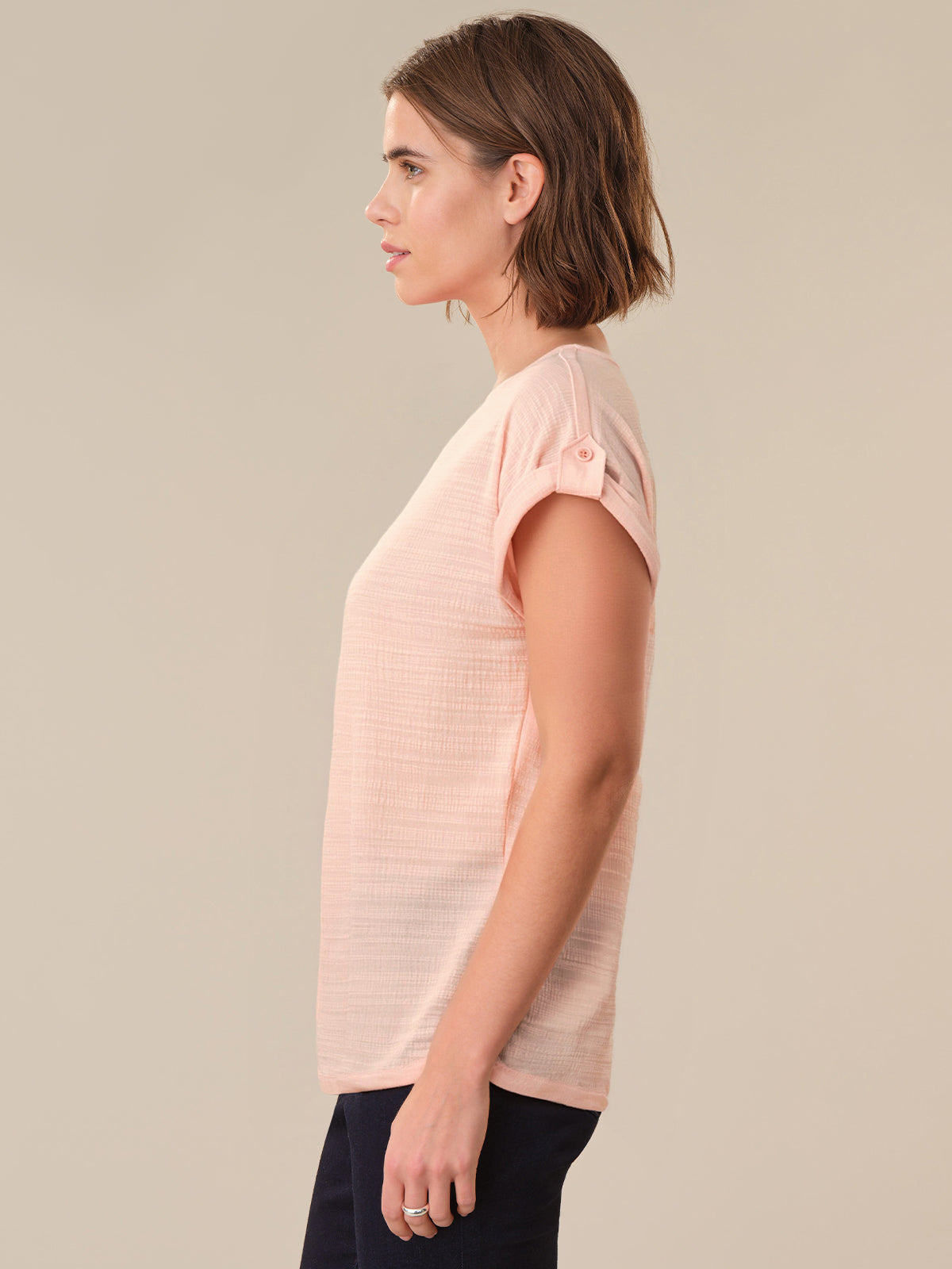 Woman wearing a light pink t-shirt against a beige background