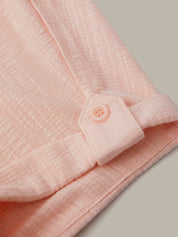 Close-up of a pink textured fabric with a button on a neutral background