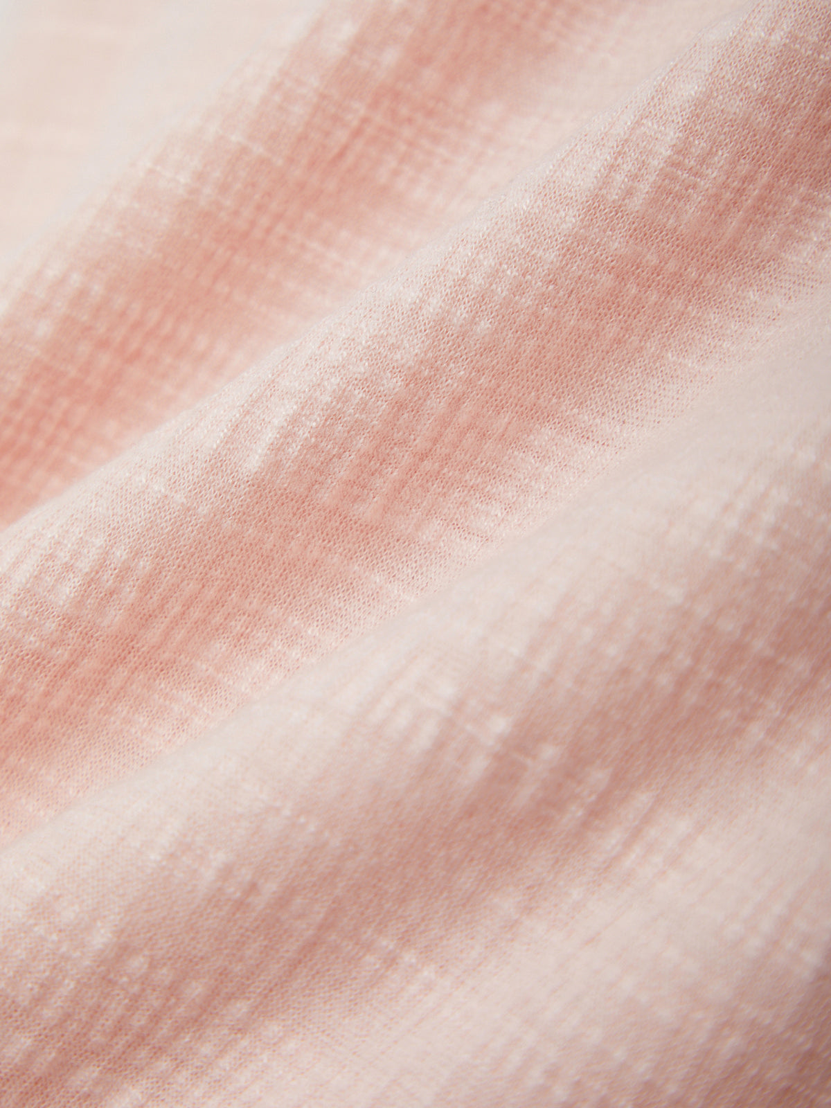 Close-up of a textured fabric with a gradient of pink and white colors.
