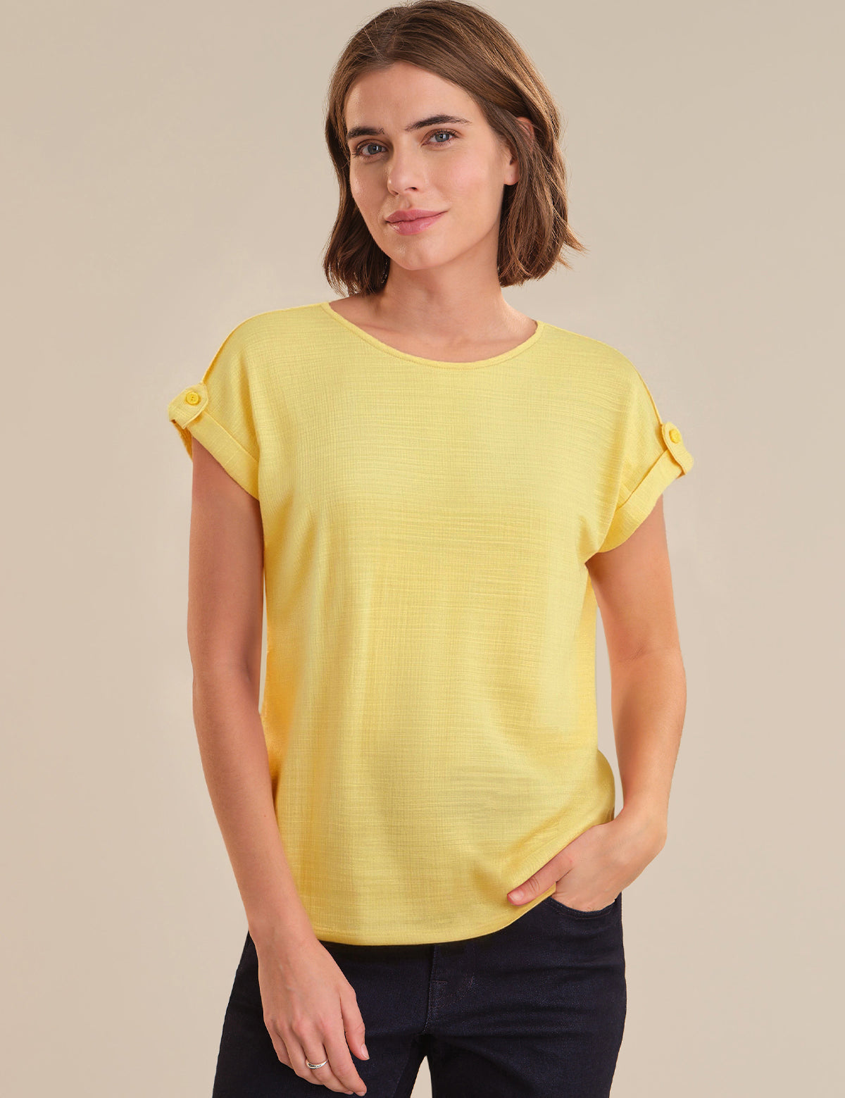 Woman wearing a yellow top against a beige background