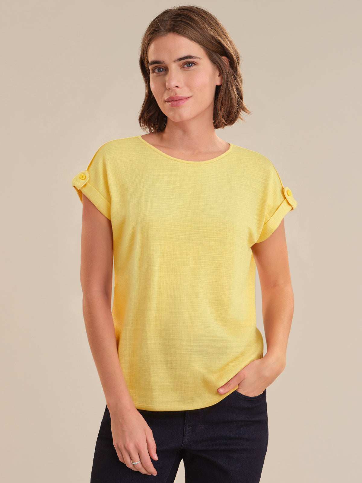 Woman wearing a yellow top against a beige background