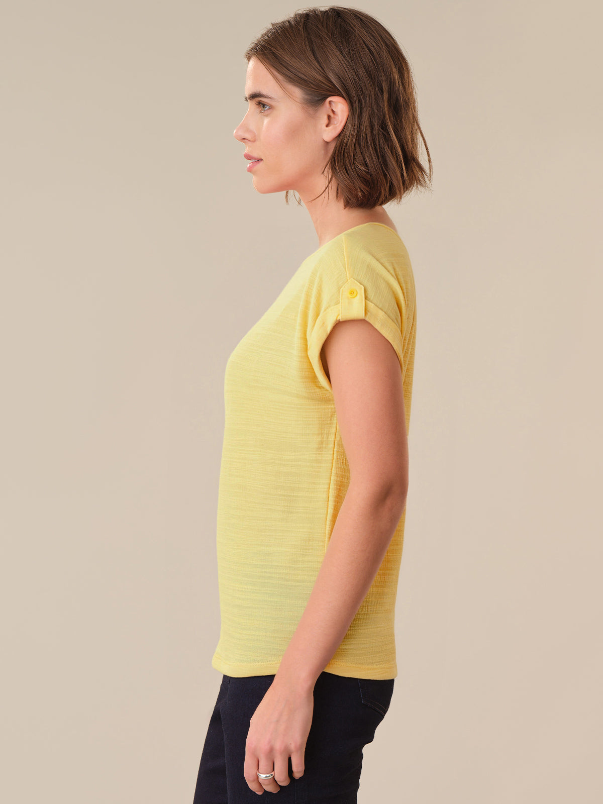 Woman wearing a yellow t-shirt against a beige background