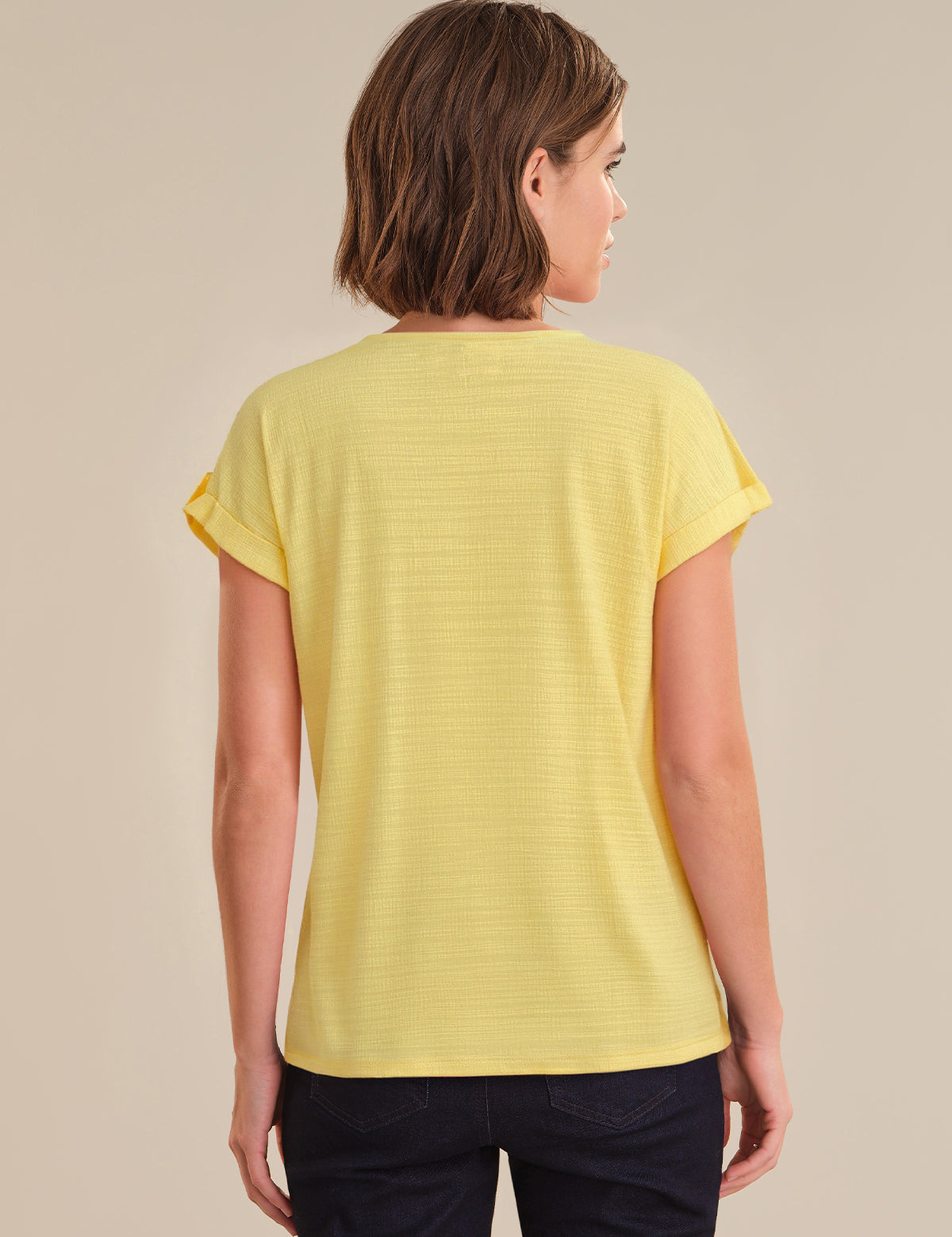 Woman wearing a yellow t-shirt against a beige background