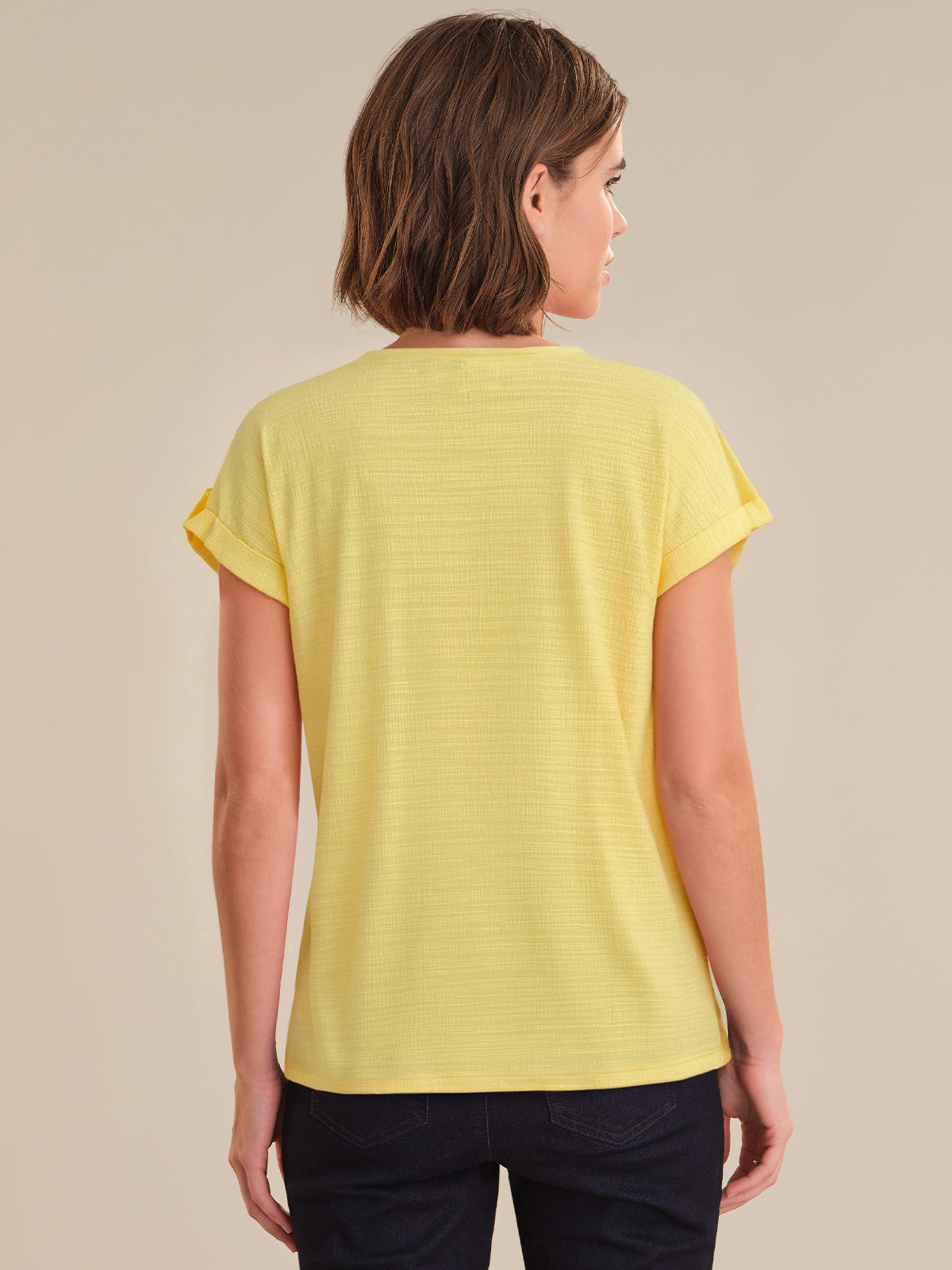 Woman wearing a yellow t-shirt against a beige background