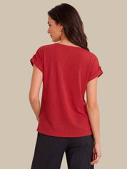 A woman shown from the back wearing a red short-sleeve top with rolled cuffs and dark pinstriped pants, against a solid beige background.