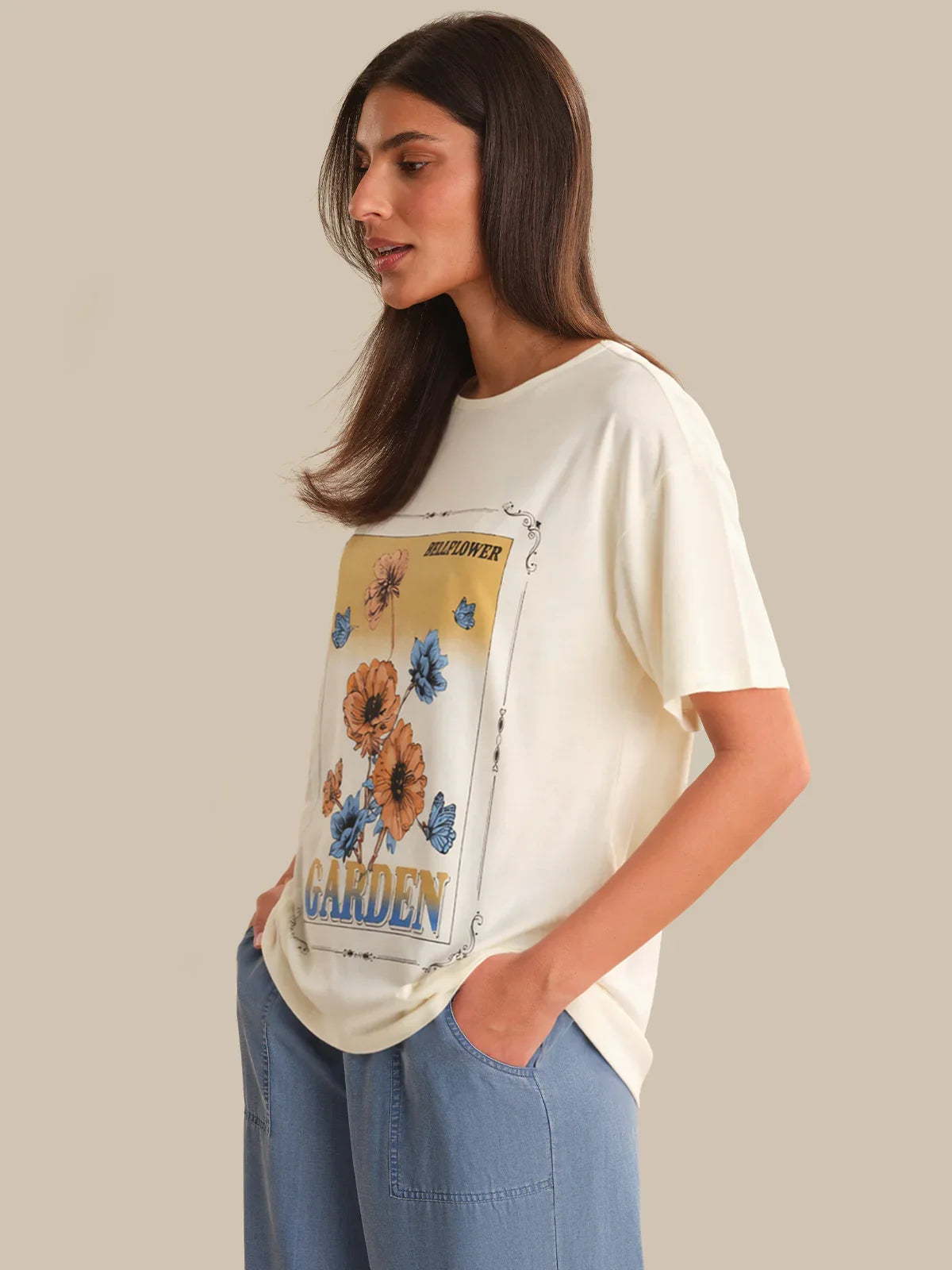 Woman wearing a white t-shirt with a floral graphic and text on a beige background