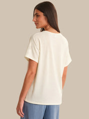 Woman wearing a white t-shirt and blue pants on a beige background