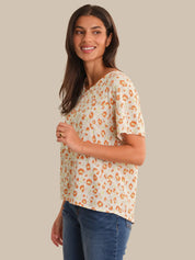 Woman wearing a leopard print top and blue jeans on a beige background