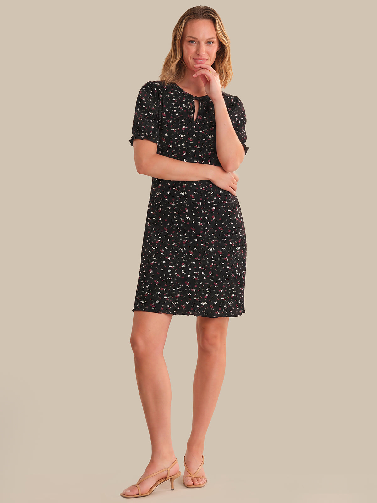 Woman wearing a black floral dress against a beige background