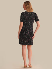 Woman wearing a black dress with white patterns on a beige background