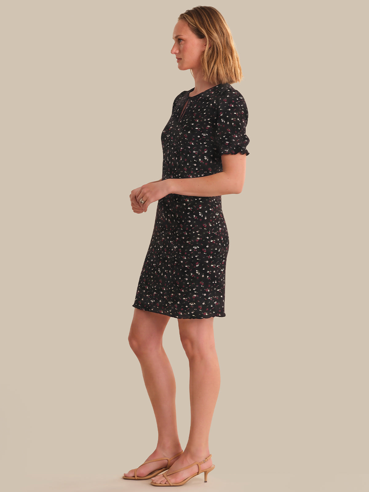 Woman wearing a black patterned dress on a beige background