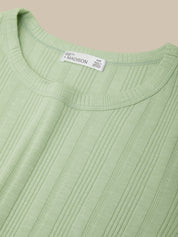 Close-up of a green sweater with a brand label on a beige background