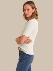 Woman wearing a white shirt and blue jeans against a plain background