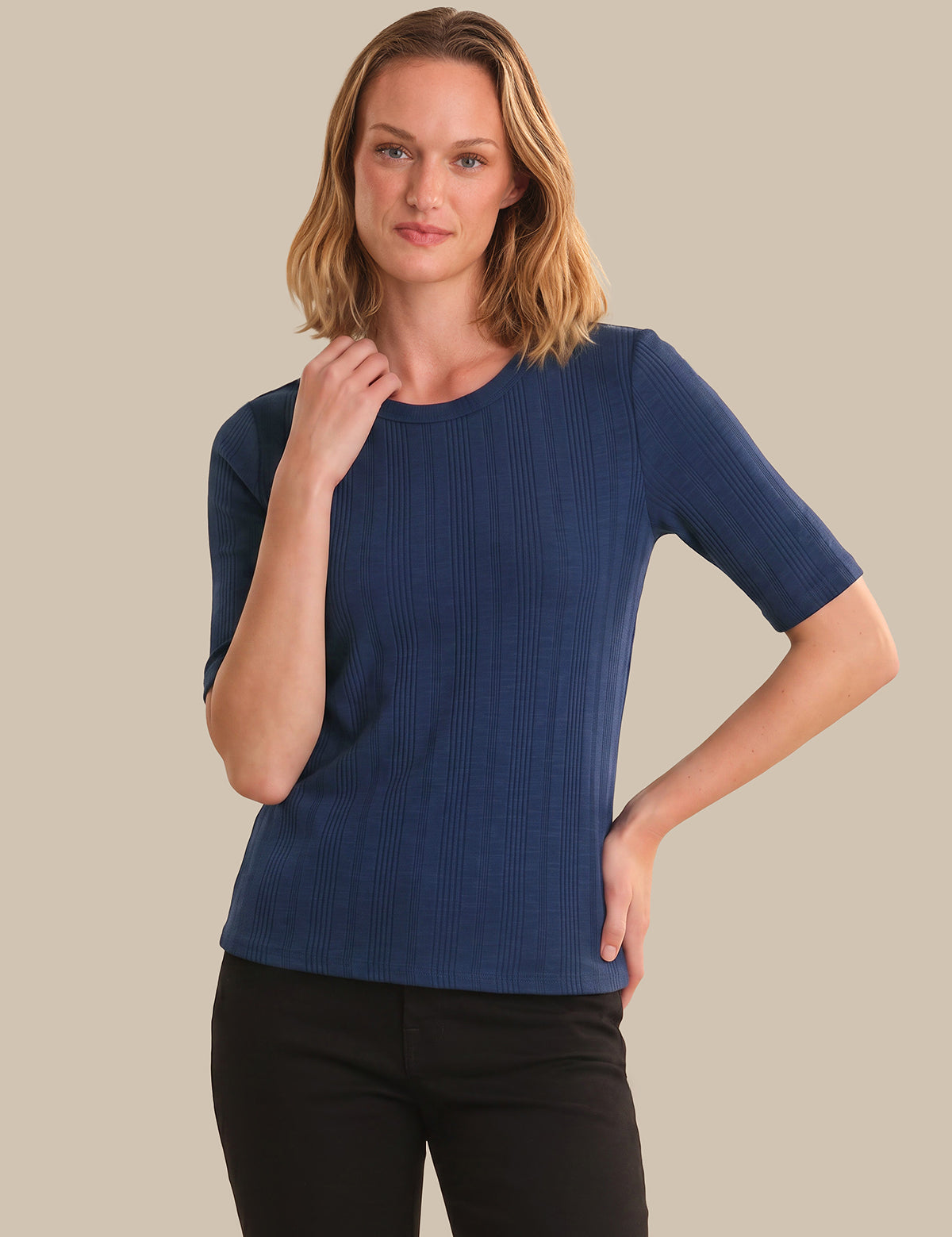 Woman wearing a blue ribbed sweater against a beige background