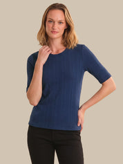 Woman wearing a blue ribbed sweater against a beige background
