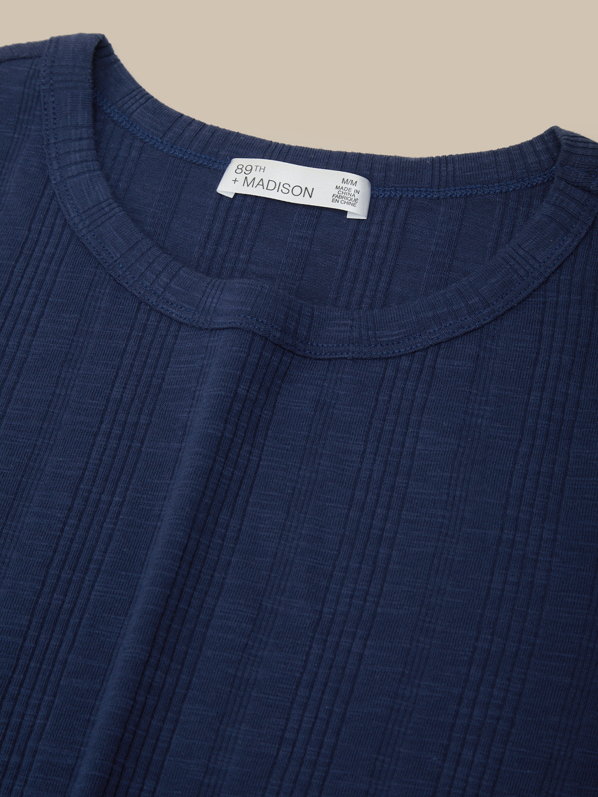 Close-up of a blue garment with a brand label on a beige background