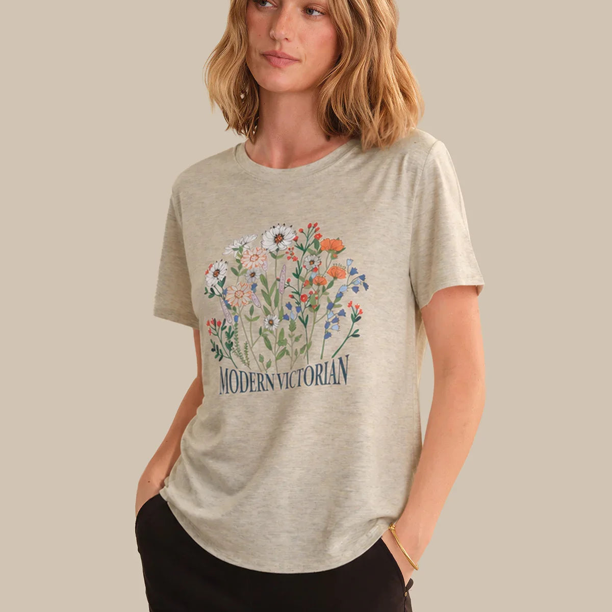 Woman wearing a beige t-shirt with floral design and 'Modern Victorian' text on a beige background