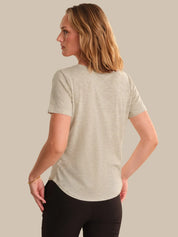 Woman wearing a light gray t-shirt and black pants against a beige background