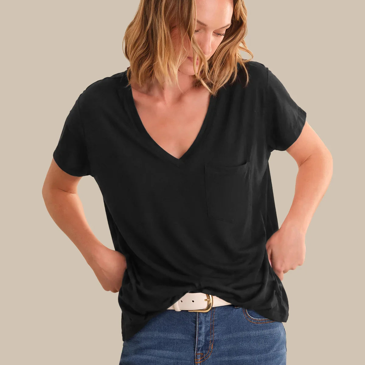 Woman wearing a black t-shirt and blue jeans against a plain background