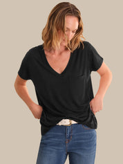 Woman wearing a black t-shirt and blue jeans against a plain background
