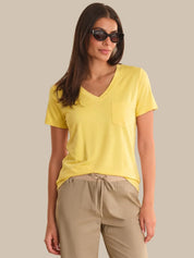 Woman wearing a yellow shirt and beige pants against a neutral background