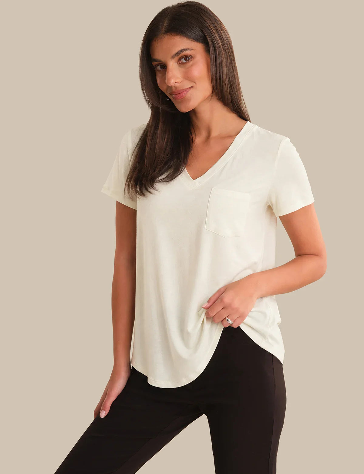 Woman wearing a white blouse and black pants on a beige background