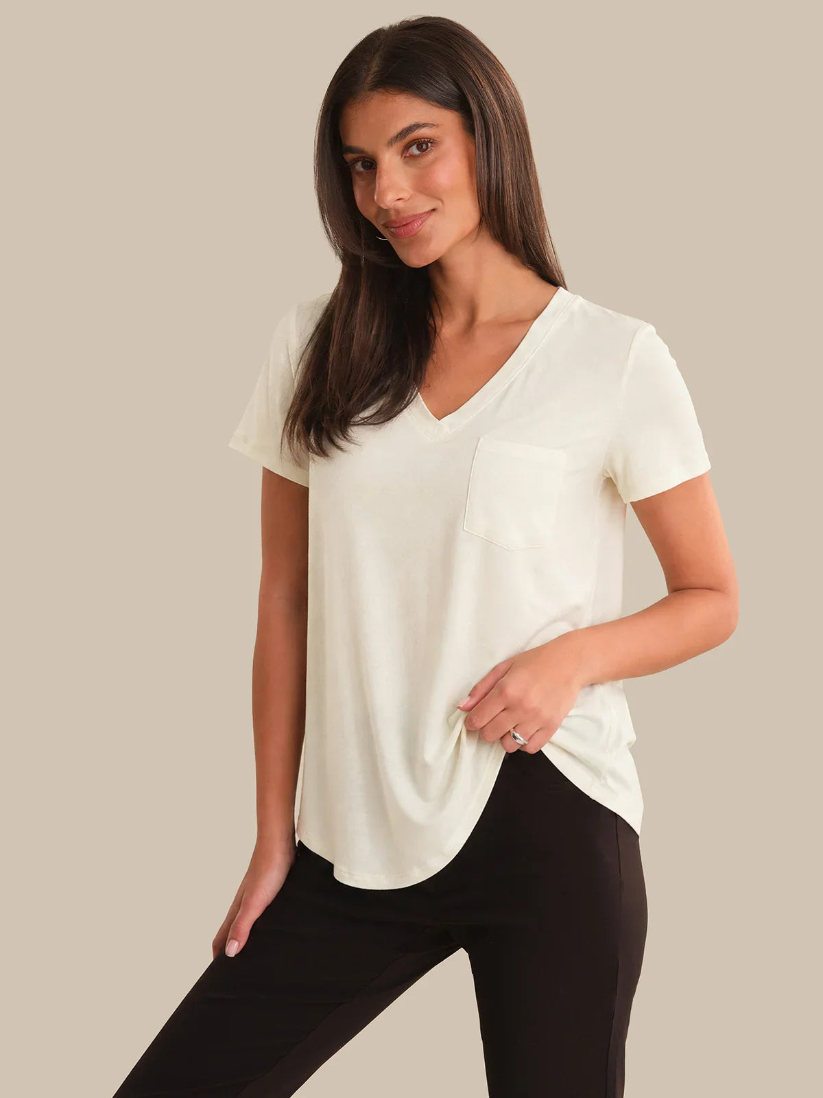Woman wearing a white blouse and black pants on a beige background