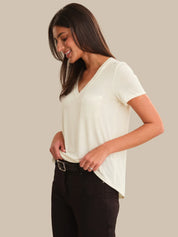 Woman wearing a white t-shirt and black pants on a beige background