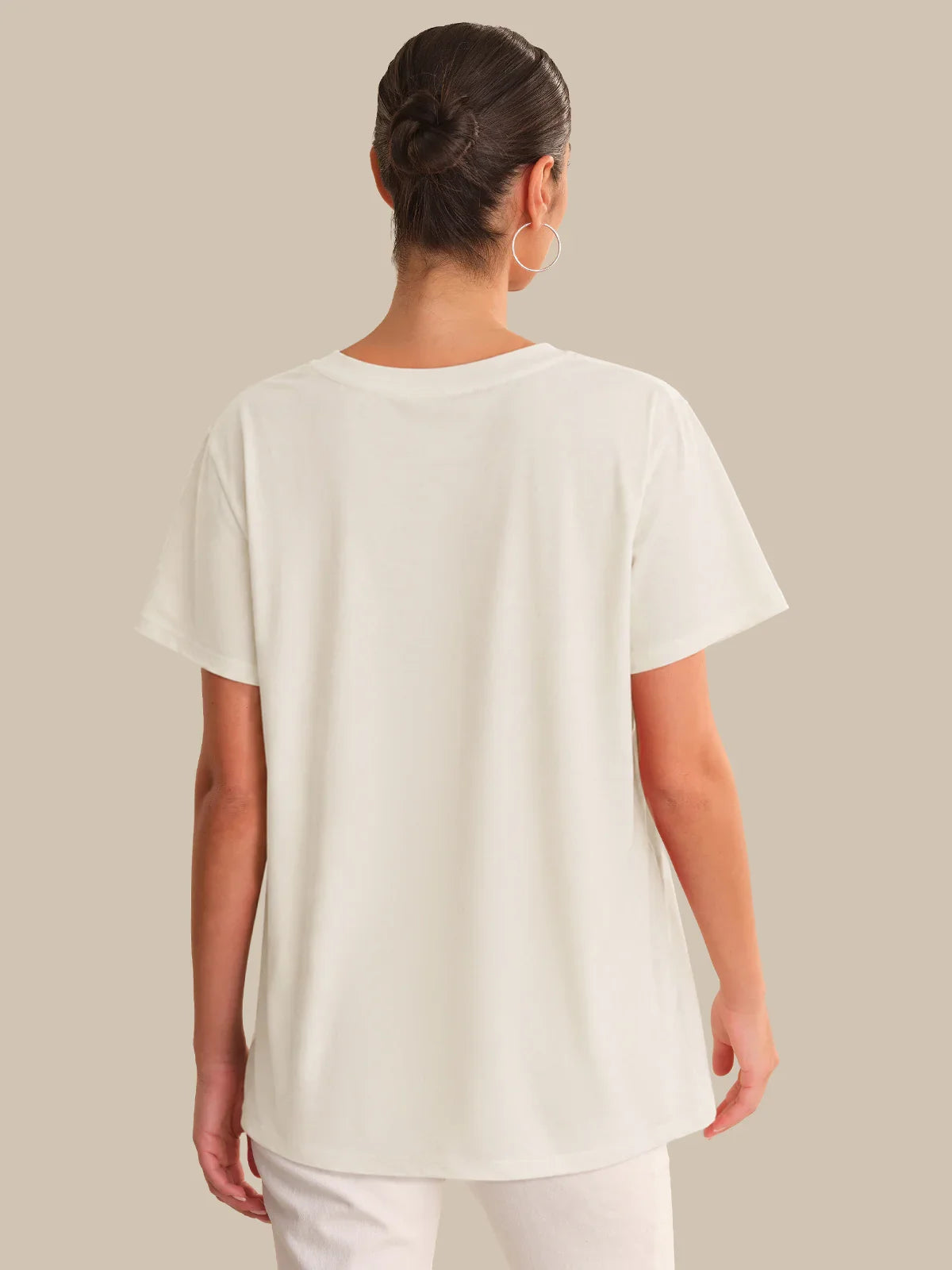 Person wearing a white t-shirt against a beige background