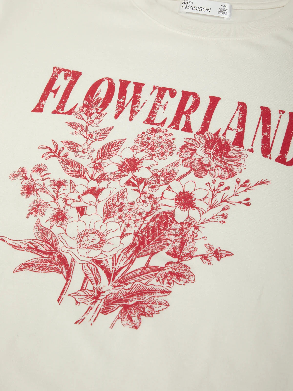 White t-shirt with red floral design and 'FLOWERLAND' text on a white background