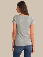 Woman wearing a gray t-shirt and blue jeans against a beige background
