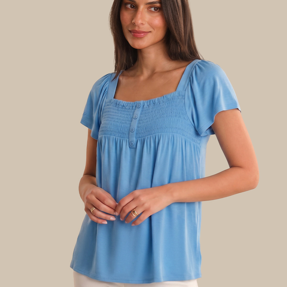 Woman wearing a blue top against a beige background
