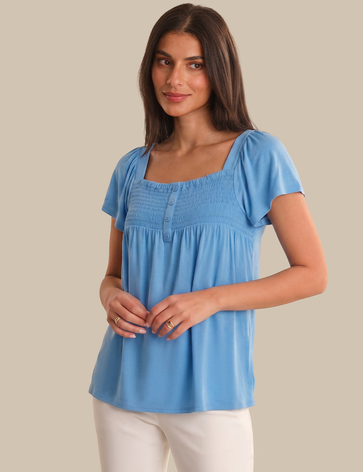 Woman wearing a blue top against a beige background