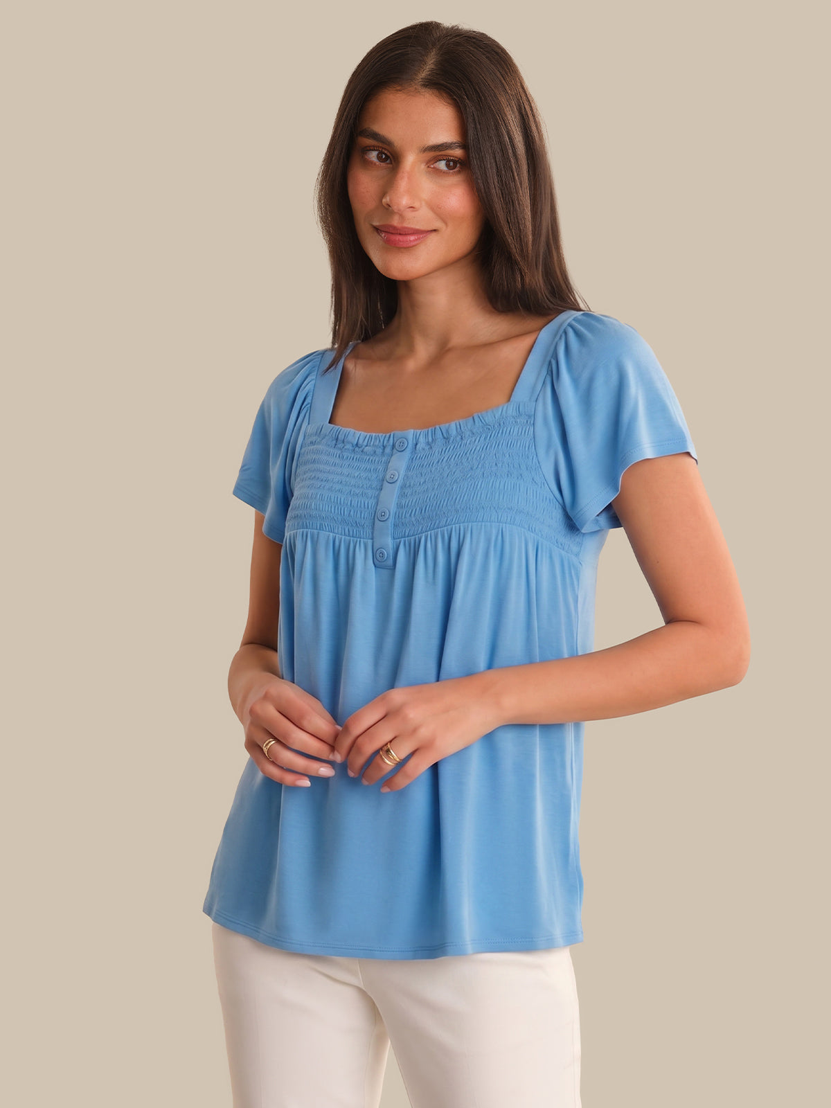 Woman wearing a blue top against a beige background
