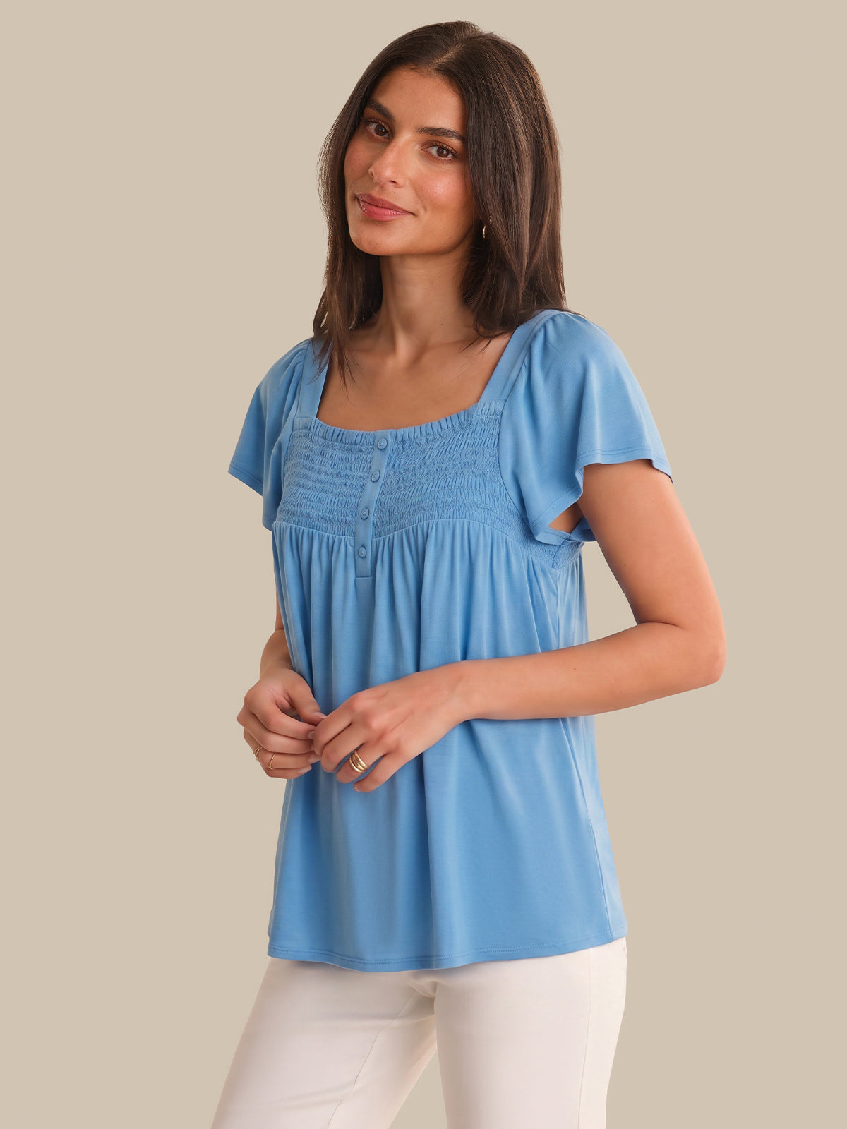 Woman wearing a blue top against a beige background