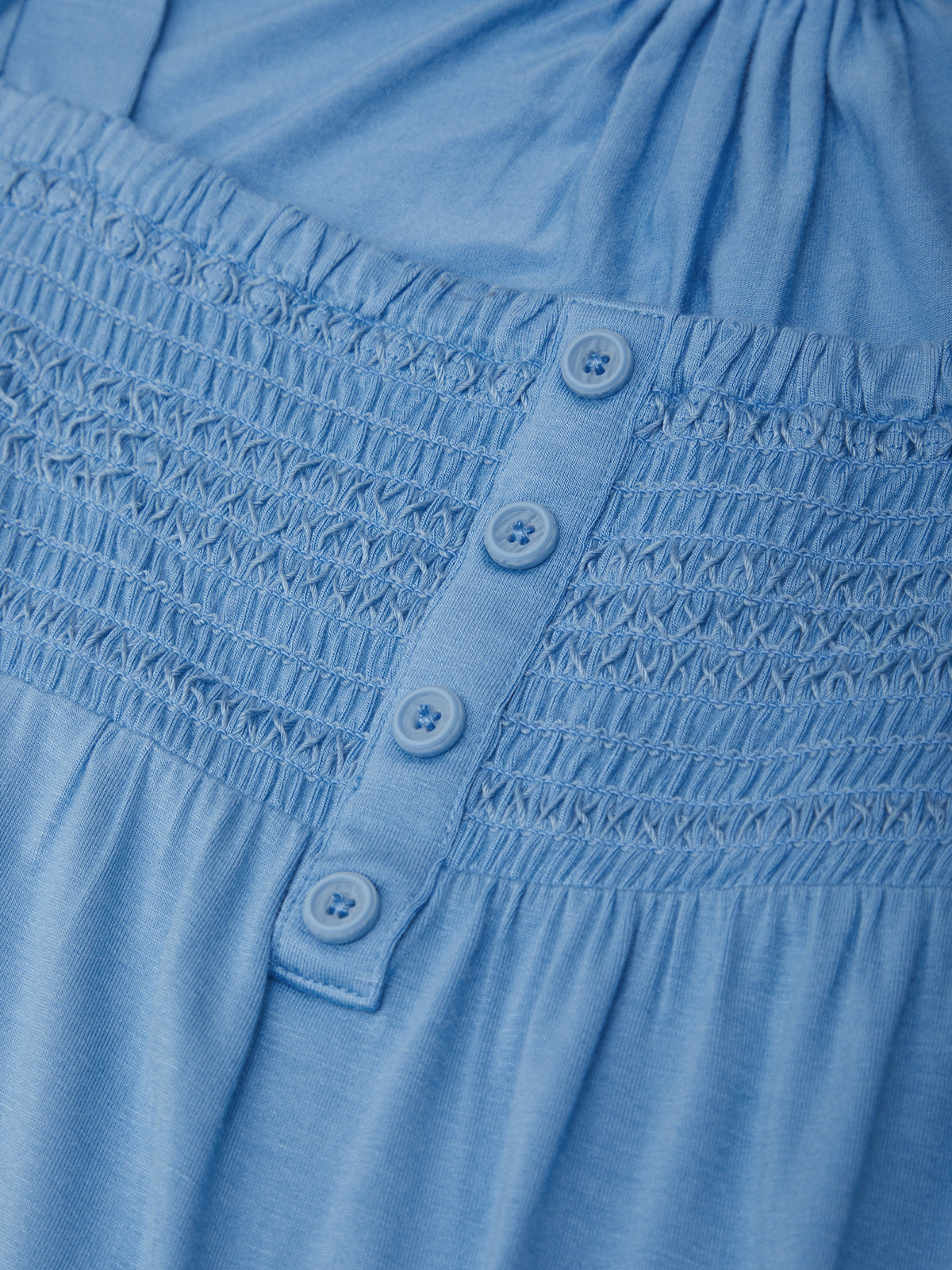 Close-up of a blue dress with smocked waist and button details